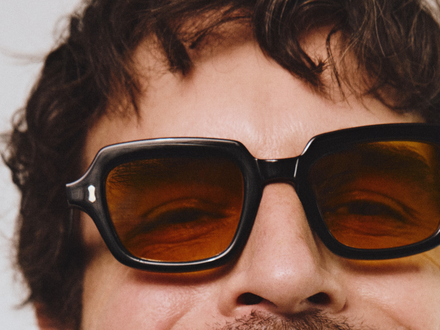 Männliches Model trägt eine Sonnenbrille mit schwarzem Kunststoffrahmen und bräunlichen Gläsern